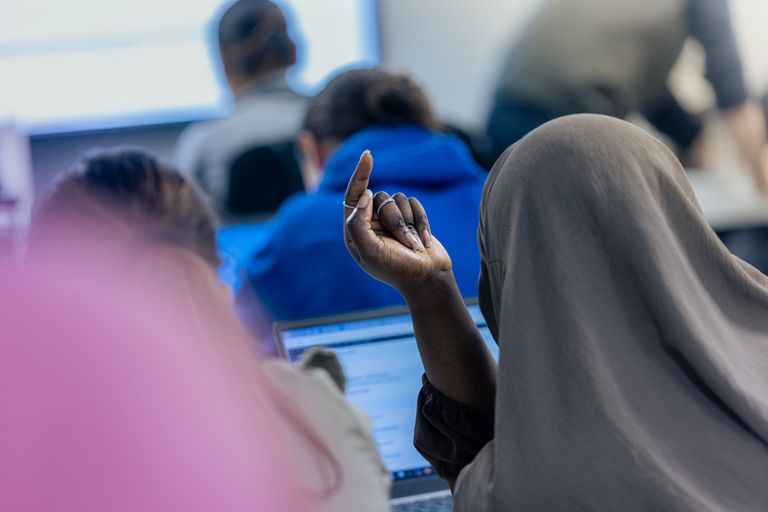 Photo d'une apprenante qui lève le doigt en cours 