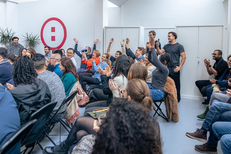 Sur cette photo il y a un grand groupe de personnes qui lèvent les bras et sourient 